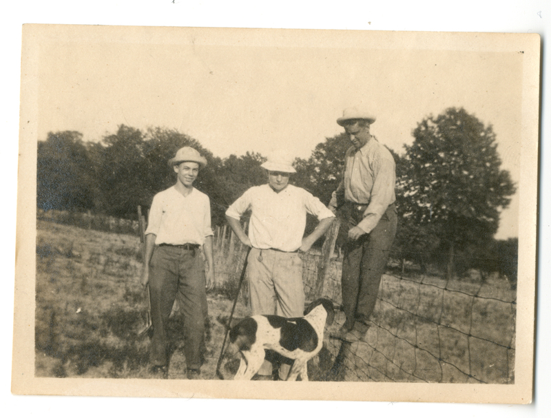 Photograph of three men and a dog outdoors on the Mudge farm in Grantfork