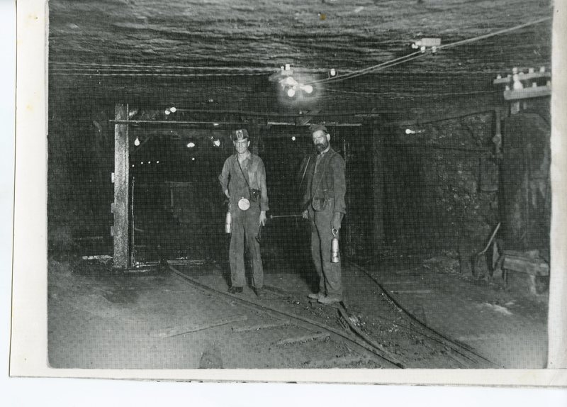 Two coal miners inside the mines standing on the tracks