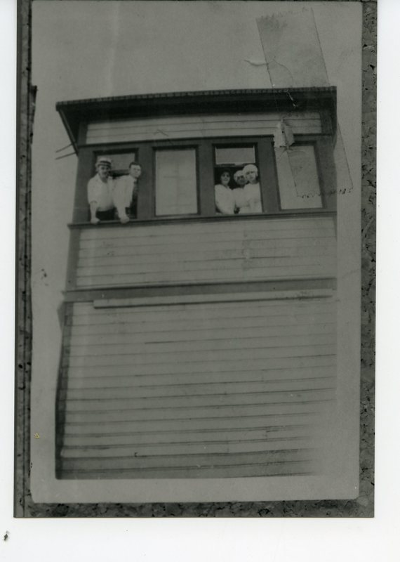 Men and women looking out of a window on the top floor of a building  