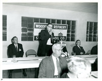 Man Presenting Behind a Table with Amoco Sign in Background